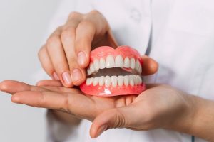 Dentist holding full dentures model showing replacement teeth options for orthodontic treatment.