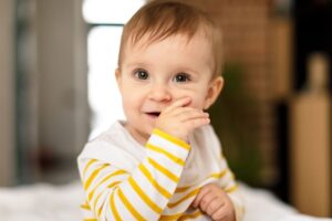 Happy toddler in yellow striped shirt showing infectious smile indoors.